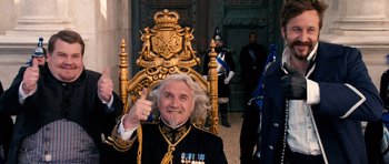 Movie still from “Gulliver's Travels” (2010), directed by Rob Letterman – An older man in a military uniform sitting in a chair; Medium shot, Low angle