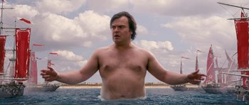 Movie still from “Gulliver's Travels” (2010), directed by Rob Letterman – A man standing in the water with his arms outstretched; Medium shot, Low angle