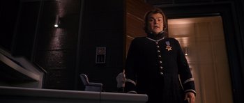 Movie still from “Gulliver's Travels” (2010), directed by Rob Letterman – A man in a black uniform standing in front of a table; Medium shot, Low angle