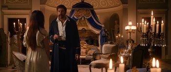 Movie still from “Gulliver's Travels” (2010), directed by Rob Letterman – A man standing in front of a fireplace holding a wine glass; Medium shot, Over the shoulder angle