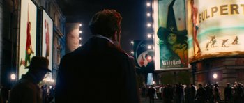 Movie still from “Gulliver's Travels” (2010), directed by Rob Letterman – A man is standing in front of a movie poster; Wide shot, Over the shoulder angle