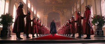 Movie still from “Gulliver's Travels” (2010), directed by Rob Letterman – A group of men in red uniforms standing on a red carpet in a room; Extreme Wide shot, Low angle