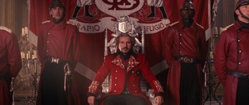 Movie still from “Gulliver's Travels” (2010), directed by Rob Letterman – A man in a red jacket sitting in a chair; Wide shot, Low angle