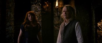 Movie still from “Gulliver's Travels” (2010), directed by Rob Letterman – A man and a woman standing next to each other in front of a stone wall; Medium shot, Low angle