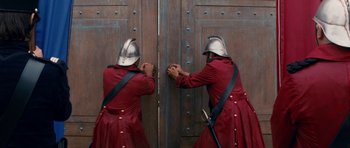 Movie still from “Gulliver's Travels” (2010), directed by Rob Letterman – Two men in red coats and helmets opening a wooden door; Medium shot, Low angle