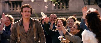 Movie still from “Gulliver's Travels” (2010), directed by Rob Letterman – A group of people standing next to each other on a street; Medium shot, Over the shoulder angle