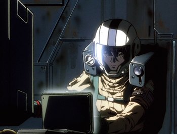 Movie still from “Gundam Wing: The Movie - Endless Waltz” (1998), directed by Yasunao Aoki – An animated character is sitting in a chair with a computer; Medium shot, Low angle