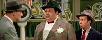 Movie still from “Guys and Dolls” (1955), directed by Joseph L. Mankiewicz – A person wearing a suit and a green hat; Medium shot, Low angle