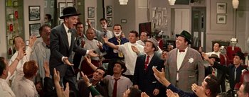 Movie still from “Guys and Dolls” (1955), directed by Joseph L. Mankiewicz – A group of men standing in a room with their hands up; Medium shot, Over the shoulder angle