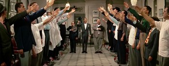 Movie still from “Guys and Dolls” (1955), directed by Joseph L. Mankiewicz – A group of men standing in a hallway with their hands raised; Wide shot, Low angle
