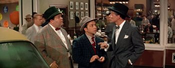 Movie still from “Guys and Dolls” (1955), directed by Joseph L. Mankiewicz – A group of men in suits and hats talking to each other; Medium shot, Over the shoulder angle