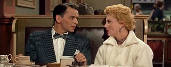 Movie still from “Guys and Dolls” (1955), directed by Joseph L. Mankiewicz – A man and a woman sitting at a table; Medium shot, Over the shoulder angle