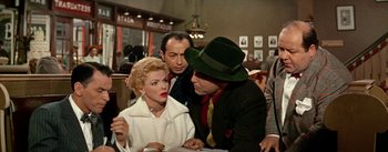Movie still from “Guys and Dolls” (1955), directed by Joseph L. Mankiewicz – A group of people standing around a table; Medium shot, Over the shoulder angle