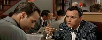 Movie still from “Guys and Dolls” (1955), directed by Joseph L. Mankiewicz – A man sitting at a table holding a spoon; Close Up shot, Over the shoulder angle