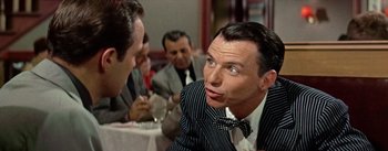 Movie still from “Guys and Dolls” (1955), directed by Joseph L. Mankiewicz – A man in a suit and a bow tie is looking at a man in a suit and a bow tie in front of him; Close Up shot, Over the shoulder angle