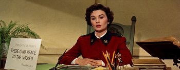 Movie still from “Guys and Dolls” (1955), directed by Joseph L. Mankiewicz – A woman sitting at a table with pencils; Medium shot, Over the shoulder angle