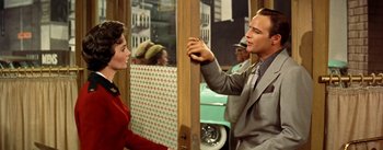 Movie still from “Guys and Dolls” (1955), directed by Joseph L. Mankiewicz – A man and a woman are standing next to each other in front of a car; Medium shot, Over the shoulder angle