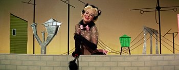 Movie still from “Guys and Dolls” (1955), directed by Joseph L. Mankiewicz – A woman dressed up as a cat and holding a broom; Medium shot, Low angle