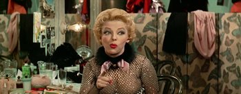 Movie still from “Guys and Dolls” (1955), directed by Joseph L. Mankiewicz – A woman with blonde hair wearing a black bow tie; Close Up shot, Over the shoulder angle