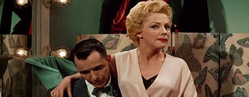 Movie still from “Guys and Dolls” (1955), directed by Joseph L. Mankiewicz – An older man and a younger woman are posing for a picture; Medium shot, Low angle