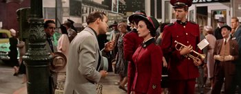 Movie still from “Guys and Dolls” (1955), directed by Joseph L. Mankiewicz – A man and a woman talking in a crowd of onlookers; Medium shot, Over the shoulder angle