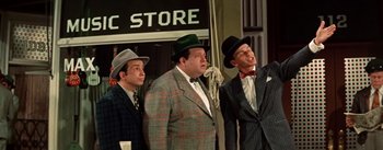 Movie still from “Guys and Dolls” (1955), directed by Joseph L. Mankiewicz – A group of men in suits and hats singing; Medium shot, Low angle