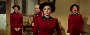 Movie still from “Guys and Dolls” (1955), directed by Joseph L. Mankiewicz – A woman in a red coat and a man in a black hat; Medium shot, Over the shoulder angle