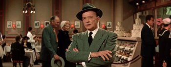 Movie still from “Guys and Dolls” (1955), directed by Joseph L. Mankiewicz – An older man wearing a green suit and a green hat; Medium shot, Over the shoulder angle