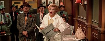 Movie still from “Guys and Dolls” (1955), directed by Joseph L. Mankiewicz – An older woman in a white coat holding a knife; Medium shot, Over the shoulder angle