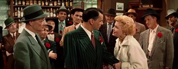 Movie still from “Guys and Dolls” (1955), directed by Joseph L. Mankiewicz – A group of people standing around each other in a room; Medium shot, Over the shoulder angle