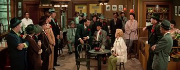 Movie still from “Guys and Dolls” (1955), directed by Joseph L. Mankiewicz – A group of men and women sitting around a table; Wide shot, High angle