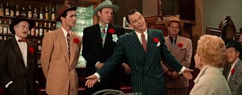 Movie still from “Guys and Dolls” (1955), directed by Joseph L. Mankiewicz – A man in a suit and tie holding his hand out to another man in a suit and tie; Medium shot, Over the shoulder angle