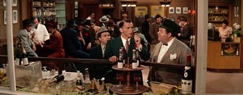 Movie still from “Guys and Dolls” (1955), directed by Joseph L. Mankiewicz – A group of men standing around each other in front of a bar; Medium shot, Over the shoulder angle