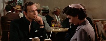 Movie still from “Guys and Dolls” (1955), directed by Joseph L. Mankiewicz – A man and a woman sitting at a table in front of drinks; Close Up shot, Over the shoulder angle