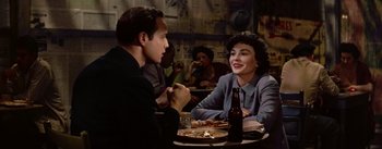 Movie still from “Guys and Dolls” (1955), directed by Joseph L. Mankiewicz – A man and a woman sitting at a dinner table; Medium shot, Over the shoulder angle