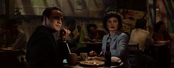 Movie still from “Guys and Dolls” (1955), directed by Joseph L. Mankiewicz – A man and a woman sitting at a dinner table; Medium shot, Low angle