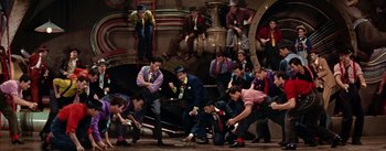 Movie still from “Guys and Dolls” (1955), directed by Joseph L. Mankiewicz – A group of men in suits and ties on a stage; Wide shot, High angle