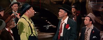 Movie still from “Guys and Dolls” (1955), directed by Joseph L. Mankiewicz – A man in a top hat talking to another man in a suit and tie; Medium shot, Low angle
