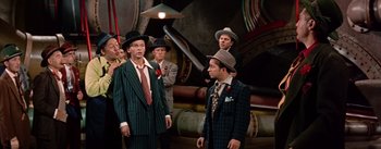 Movie still from “Guys and Dolls” (1955), directed by Joseph L. Mankiewicz – A group of men in suits and hats standing next to each other; Medium shot, Low angle