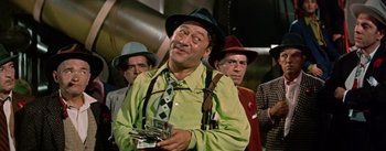 Movie still from “Guys and Dolls” (1955), directed by Joseph L. Mankiewicz – A group of men standing next to each other holding money; Medium shot, Low angle