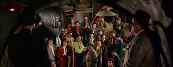 Movie still from “Guys and Dolls” (1955), directed by Joseph L. Mankiewicz – A group of men standing next to each other; Wide shot, High angle