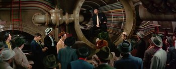 Movie still from “Guys and Dolls” (1955), directed by Joseph L. Mankiewicz – A group of men in suits and hats in front of a machine; Wide shot, High angle