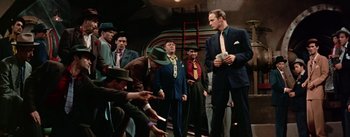 Movie still from “Guys and Dolls” (1955), directed by Joseph L. Mankiewicz – A group of men standing around each other holding money; Medium shot, Low angle