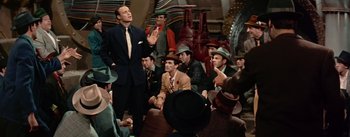 Movie still from “Guys and Dolls” (1955), directed by Joseph L. Mankiewicz – A group of men sitting in a room with hats on; Medium shot, Low angle