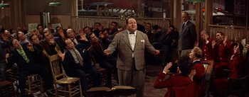 Movie still from “Guys and Dolls” (1955), directed by Joseph L. Mankiewicz – A group of people sitting in front of a microphone; Medium shot, High angle