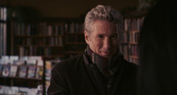 Movie still from “Hachi: A Dog's Tale” (2009), directed by Lasse Hallström – A man in a jacket and scarf in a room; Close Up shot, Over the shoulder angle