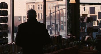 Movie still from “Hachi: A Dog's Tale” (2009), directed by Lasse Hallström – An older man sitting in front of a large window; Medium shot, Over the shoulder angle