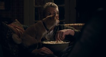 Movie still from “Hachi: A Dog's Tale” (2009), directed by Lasse Hallström – A man sitting on a couch with a dog eating popcorn; Medium shot, High angle