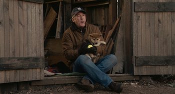 Movie still from “Hachi: A Dog's Tale” (2009), directed by Lasse Hallström – An older man sitting on the ground holding a dog; Medium shot, High angle