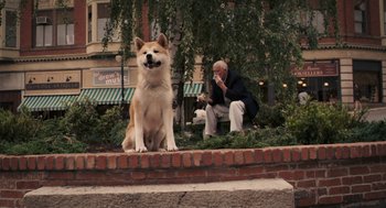Movie still from “Hachi: A Dog's Tale” (2009), directed by Lasse Hallström – A dog sitting on the ground next to a man; Wide shot, Low angle